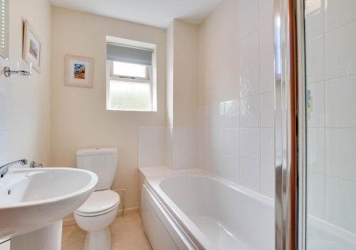 a white bathroom with a toilet and a sink at Ash Cottage in Beer