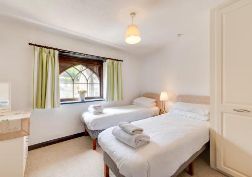 a bedroom with two beds and a window at Chart Cottage in Beer