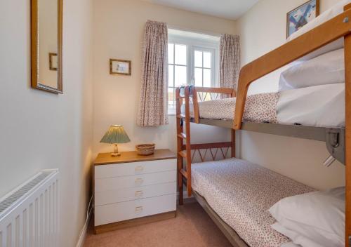 a bedroom with two bunk beds and a window at Farthings in Salcombe Regis