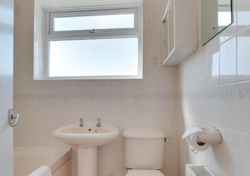 a bathroom with a sink and a toilet and a window at Farthings in Salcombe Regis