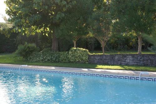 a swimming pool with trees and a stone wall at Villa Les Folies - magnifique jardin avec piscine in Le Beausset