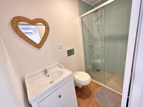 uma casa de banho com um WC, um lavatório e um espelho. em Setubal Beach Vibes - Pátio em Setúbal
