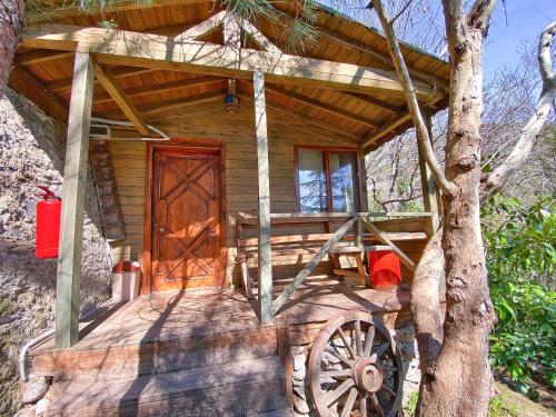 eine Holzhütte mit einer großen Holztür und einem Baum in der Unterkunft Antik Vadi Bungalow in Edremit