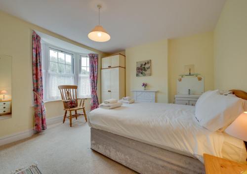 a bedroom with a large bed and a chair at Glenisla in Sidmouth