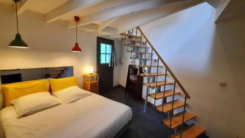 a bedroom with a bed and a spiral staircase at Gîte avec piscine et jacuzzi partagés en Cévennes in Cros
