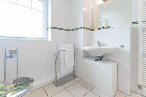 a white bathroom with a sink and a toilet at Strandvilla 27, Turmwohnung in Scharbeutz