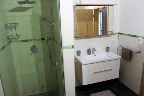 La salle de bains est pourvue d'un lavabo et d'une douche. dans l'établissement Ferienwohnung am Einödhof, à Uttendorf