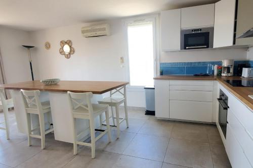 une cuisine avec des armoires blanches et une table en bois dans l'établissement Spacious T4 with sea and Esterel views, à Saint-Raphaël