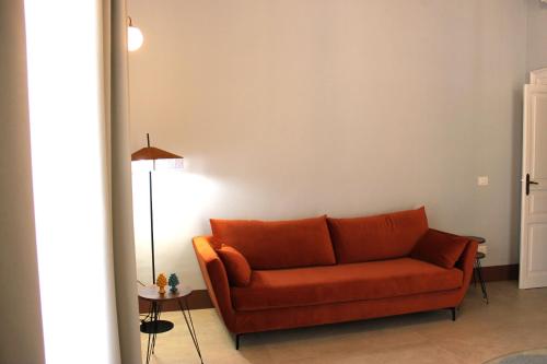 an orange couch in a living room with a lamp at Palazzo sul Corso-Charming Appartaments in Brindisi