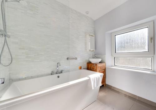 a white bath tub in a bathroom with a window at Victoria Cottage in Beer