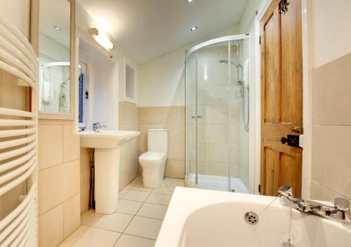 a bathroom with a tub and a shower and a sink at West View Cottage in Beer