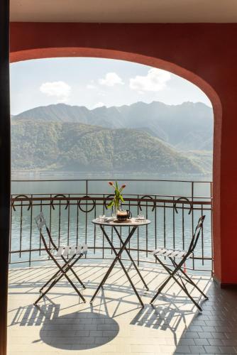 a table and chairs on a balcony with a view of the water at 76 The Lake House - Lugano in Melide