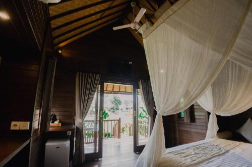 a bedroom with a bed with white curtains in it at Sunset Star Huts in Nusa Lembongan