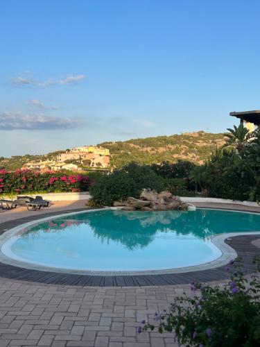 a large swimming pool in a resort with a hill in the background at Appartamento Gli Oleandri 138 - Costa Smeralda-Porto Cervo in Liscia di Vacca