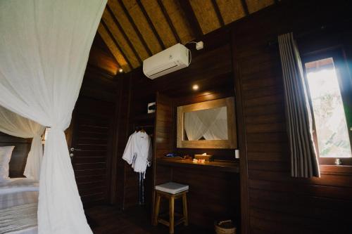 1 dormitorio con 1 cama con cortina blanca y ventana en Sunset Star Huts, en Nusa Lembongan