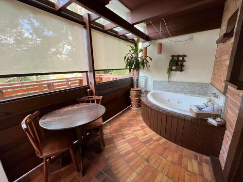 La salle de bains est pourvue d'une table et d'une baignoire. dans l'établissement Pousada Kaloa Eco Village, à Bombinhas