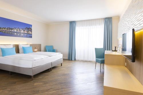 a hotel room with a bed and a desk at Hotel IV Jahreszeiten Lübeck in Lübeck