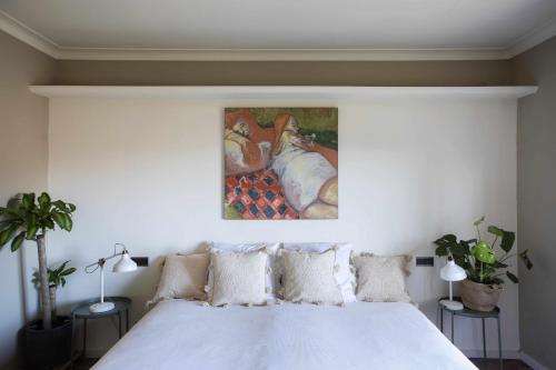 a bedroom with a white bed with a painting on the wall at unic views begur, alojamiento turístico in Begur
