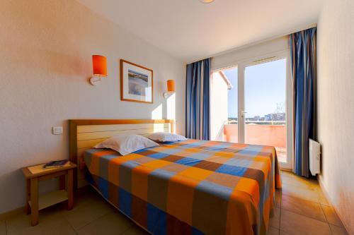 a bedroom with a bed and a large window at Lagrange Vacances Catalana in Le Barcarès