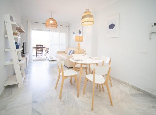 a dining room and living room with a table and chairs at SibsSanlucar Piletas 1ª Linea Playa Piscina Terraza Padel Parking Wifi in Sanlúcar de Barrameda