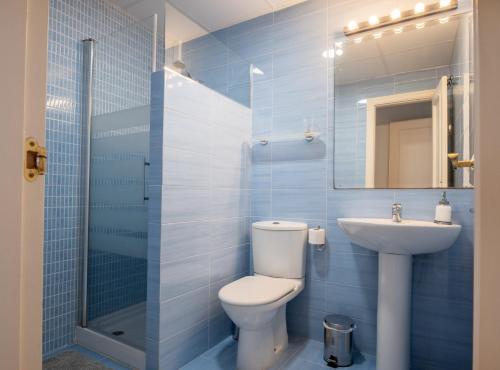 a blue tiled bathroom with a toilet and a sink at SibsSanlucar Piletas 1ª Linea Playa Piscina Terraza Padel Parking Wifi in Sanlúcar de Barrameda