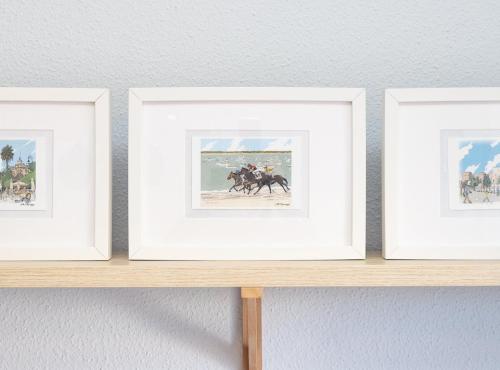 three framed photographs of a horse race on a shelf at SibsSanlucar Piletas 1ª Linea Playa Piscina Terraza Padel Parking Wifi in Sanlúcar de Barrameda