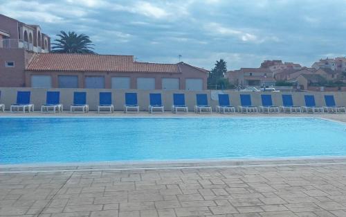 une grande piscine bleue avec des chaises et un bâtiment dans l'établissement Lagrange Vacances Catalana, au Barcarès
