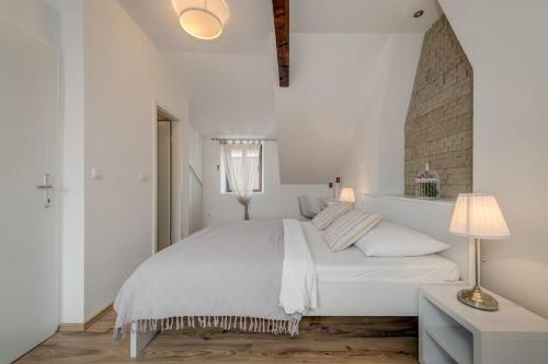 a white bedroom with a large bed and a lamp at 3 bedrooms charming stone house in old town in Trogir