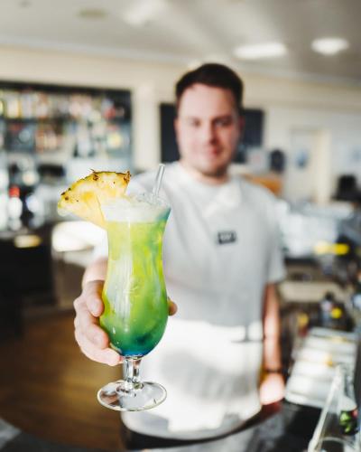 a man is holding a drink with a piece of pizza at Hotel IV Jahreszeiten Lübeck in Lübeck