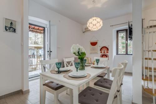 a white dining room with a white table and chairs at 3 bedrooms charming stone house in old town in Trogir