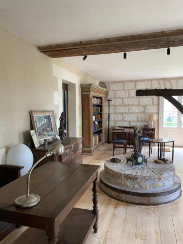 a living room with a table and a stone fireplace at Moulin de Battereau - Jardin & Verger - 9km d'Amboise in Saint-Martin-le-Beau