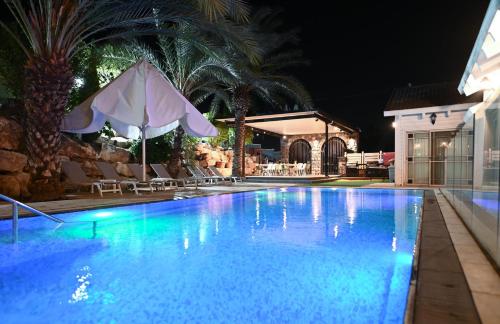 a swimming pool at night with an umbrella and chairs at YalaRent - Liri Resort in Tiberias