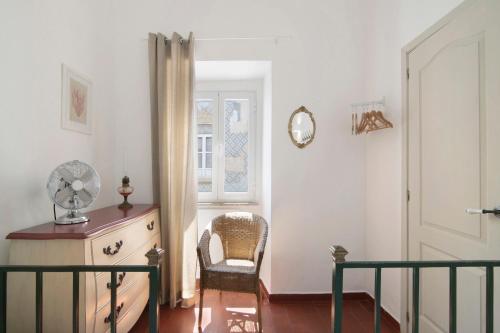 um quarto com uma cadeira, uma cómoda e uma janela em Casa Limoeiro em Albufeira