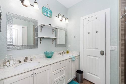a white bathroom with a sink and a mirror at A Wave From It All - The Ocean Aire, 30 secs from the sand! in Galveston
