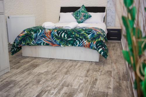 a bedroom with a bed with a white bedspread and wooden floors at LUXURY ERK in Călimăneşti