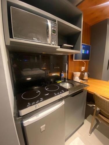 uma cozinha com um fogão e um micro-ondas em SEM TAXAS! Ap Lindo, Central c/ Garagem. em Pelotas