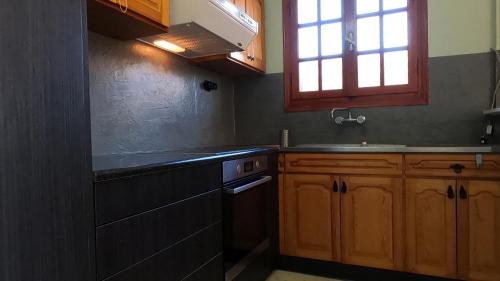 a kitchen with wooden cabinets and a sink and a window at Holiday apartment near the sea in Melission