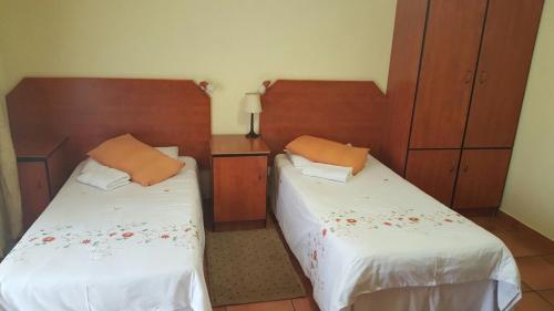 - une chambre avec 2 lits et des têtes de lit en bois dans l'établissement Deletz Guesthouse, à Witbank
