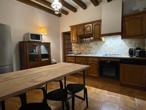 une cuisine avec des armoires en bois et une table en bois dans l'établissement Maison chaleureuse avec cheminée, à Beychac-et-Caillau