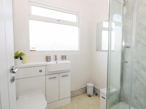 a white bathroom with a sink and a shower at Dolly's Lookout in Lowestoft