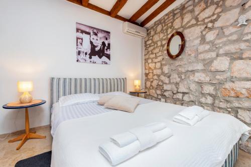 a bedroom with a white bed and a stone wall at Revera Rooms in Rovinj