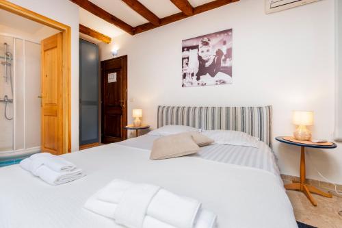 a bedroom with a large white bed with two lamps at Revera Rooms in Rovinj