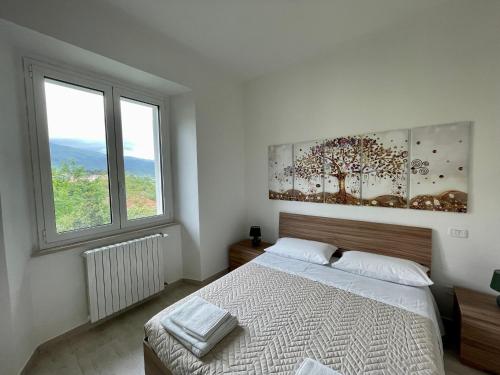 a white bedroom with a bed and two windows at Dama Dama in Guardiagrele