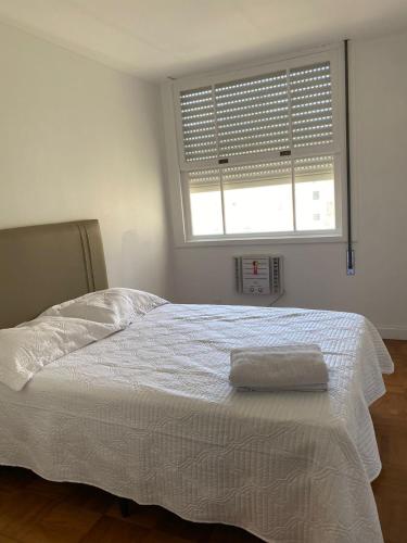 1 dormitorio con 1 cama blanca y ventana en COPACABANA RIO PRAIA 12 en Río de Janeiro