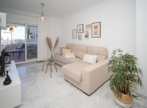 a living room with a couch and two potted plants at SibsSanlucar Donana 1ª Línea Playa-Piscina-Padel in Sanlúcar de Barrameda