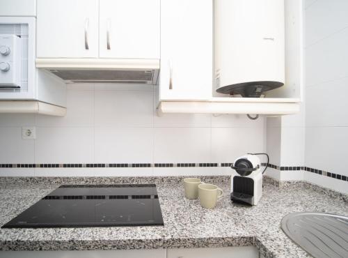 a kitchen with white cabinets and a counter top at SibsSanlucar Donana 1ª Línea Playa-Piscina-Padel in Sanlúcar de Barrameda