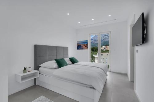 um quarto branco com uma cama e uma televisão de ecrã plano em Apartment Ocean View em Tučepi