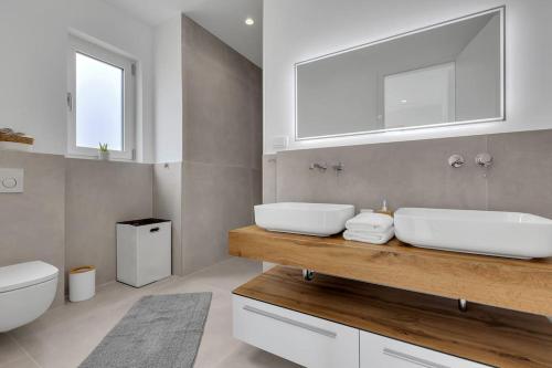 a bathroom with two sinks and a toilet and a mirror at Apartment Ocean View in Tučepi