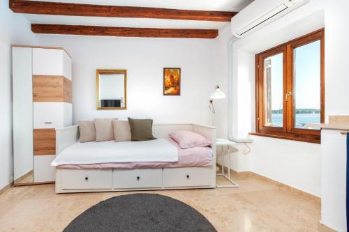 a white bedroom with a bed and a window at Revera Rooms in Rovinj