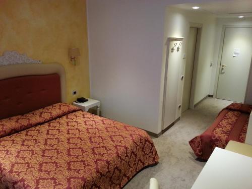 a bedroom with two beds and a red bedspread at Palace Hotel & SPA La CONCHIGLIA D' ORO in Vicenza